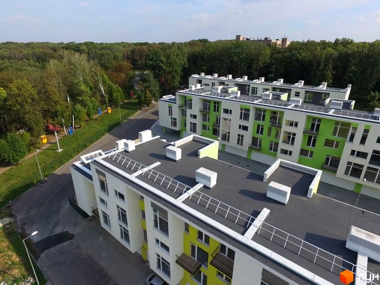 Зображення Житлового комплексу Shatilovka Hillside. Вид зверху на новобудову з білими стінами та зеленими вставками, поруч зелена зона з деревами.