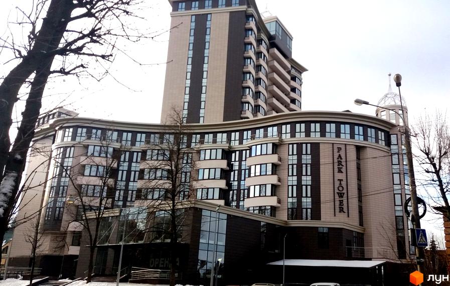 Житловий комплекс Park Tower – це висотна будівля з вигнутим фасадом, великою кількістю скління та балконами. На фасаді є назва комплексу.