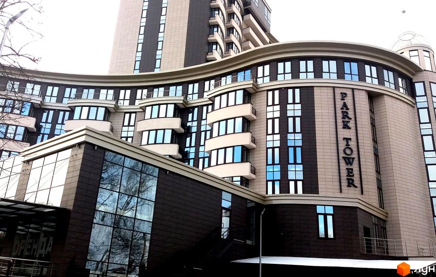 Житловий комплекс Park Tower - це сучасна новобудова з вигнутим фасадом та великою кількістю скління. На фасаді видно назву комплексу 
