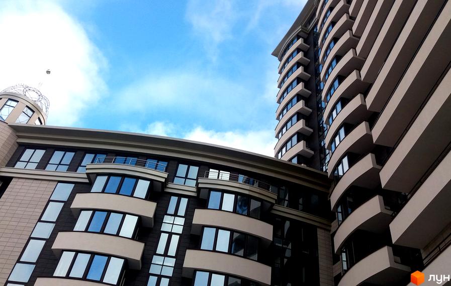 Житловий комплекс Park Tower - сучасна архітектура з вигнутими балконами та панорамними вікнами на тлі блакитного неба. Зовнішній вигляд новобудови вражає своєю елегантністю та масштабом.