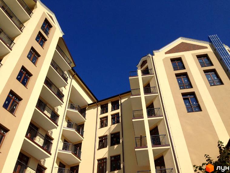 Фасад багатоповерхового житлового комплексу на вул. Лисенка, 16/20. Будинки світлого кольору з балконами та темними вікнами під блакитним небом.