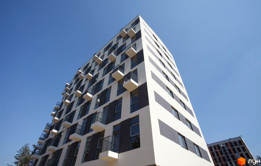 Висотна новобудова Park Town з біло-сірим фасадом та балконами. Яскраве блакитне небо над будинком.