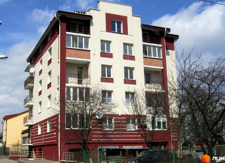 Житловий комплекс на вул. Чижевського, 6: світлий фасад з темно-червоними елементами, балконами та вікнами. Перед будинком видно дерева.