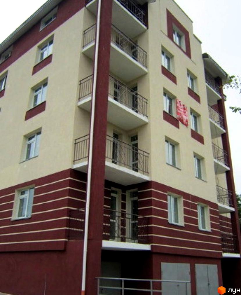 Багатоквартирна новобудова на вул. Чижевського, 6 з бежевим та темно-червоним фасадом, горизонтальними смугами, балконами та гаражами на першому поверсі.