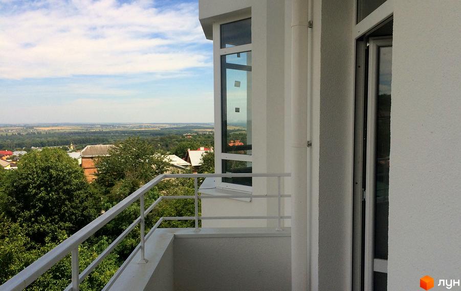 Балкон з білою огорожею та видом на зелені дерева та місто. Зовнішній вигляд новобудови ЖК Kaiser.