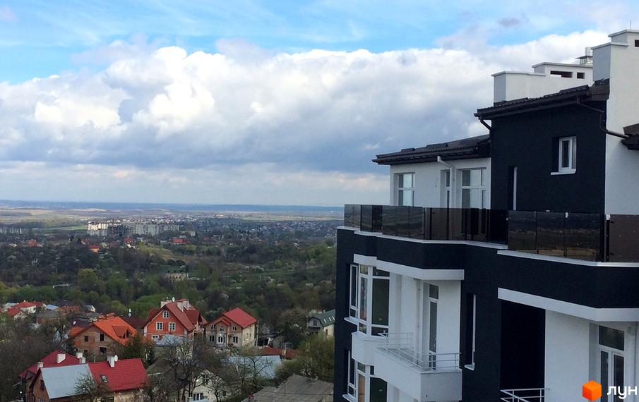 Вид на новобудову ЖК Kaiser з чорно-білим фасадом та скляними балконами. Навколо розташовані житлові будинки та зелені насадження.