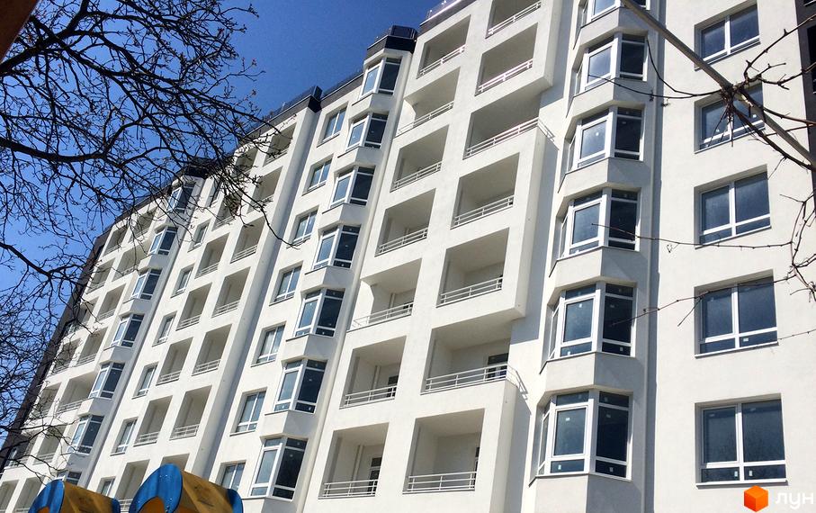 Зовнішній вигляд новобудови ЖК Kaiser з численними балконами та великими вікнами. Будинок має білий фасад та розташований на фоні блакитного неба.