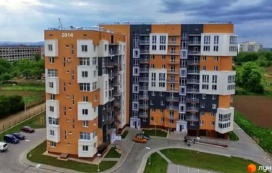Житловий комплекс Галактика. На зображенні багатоповерховий будинок з помаранчевими, сірими та білими фасадами, а також прибудинкова територія з парковкою та зеленими газонами.