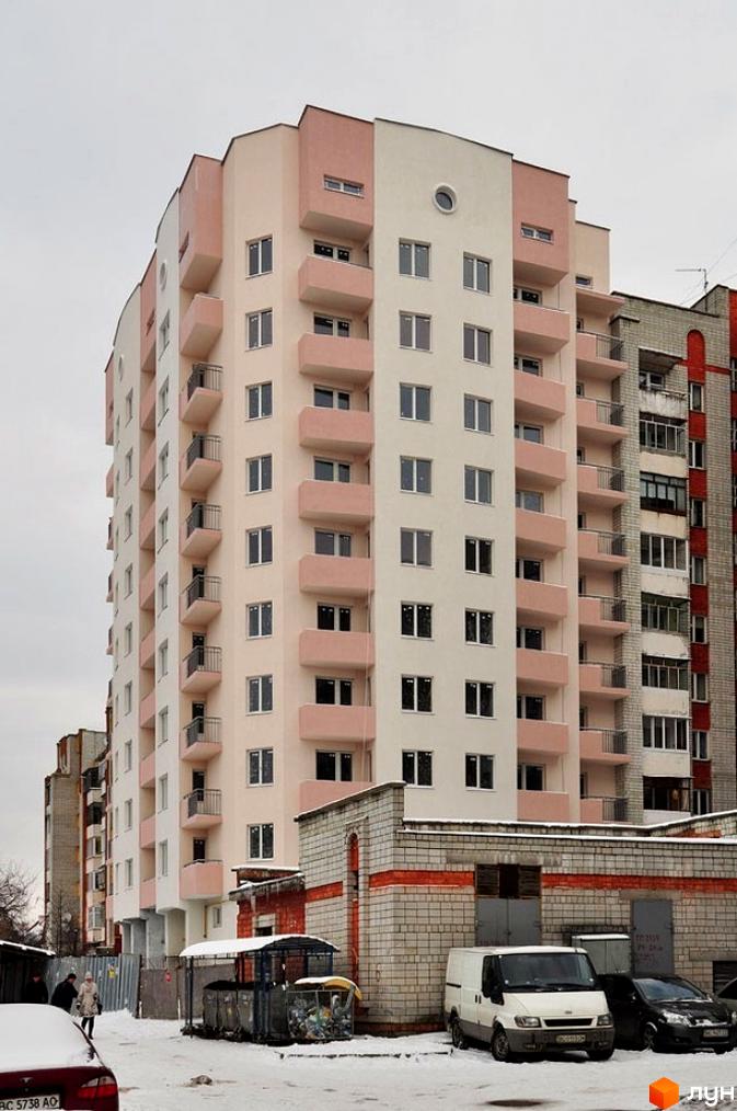 Багатоповерхова новобудова бежевого та рожевого кольорів з балконами на вулиці Григорія Грабянки, 5. Навколо засніжена територія з автомобілями.