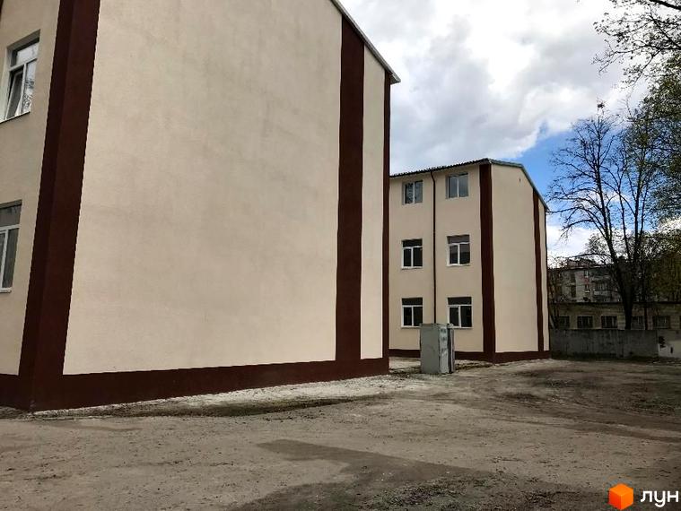 Житловий комплекс Садове місто: будівлі з бежевими фасадами та коричневими смугами. Навколо територія з гравієм та деревами.