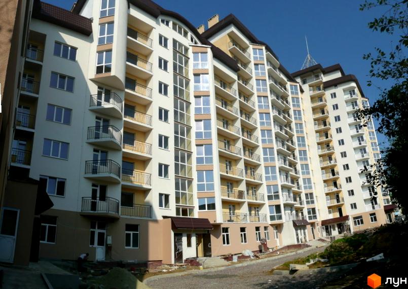 Житловий комплекс на вул. Караджича, 29: багатоповерховий будинок світлих тонів з балконами та великими вікнами. Видно облаштування прибудинкової території.