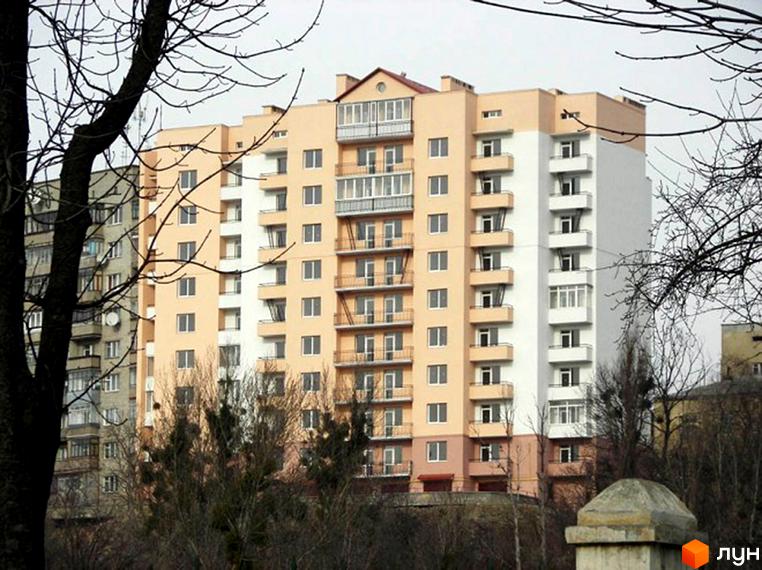 Житловий комплекс на вул. Золота, 15а з бежево-білим фасадом та численними балконами. На передньому плані видно дерева без листя та елементи прибудинкової території.
