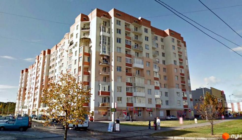 Багатосекційний житловий комплекс за адресою просп. Червоної Калини, 64, з біло-бежевим фасадом та коричневими акцентами. На прибудинковій території видно дерева та припарковані авто.