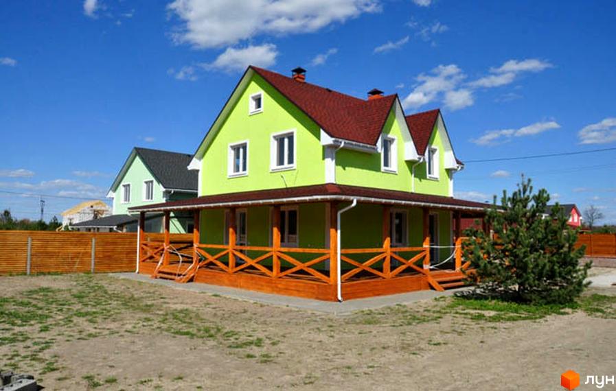 Будинок в Котеджному містечку HappyTown: яскраво-зелений фасад, червоний дах, дерев'яна тераса. Навколо ділянка з молодим деревом та дерев'яним парканом.