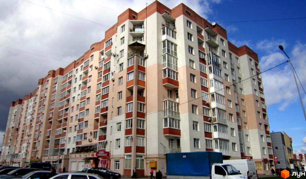 Новобудова на просп. Червоної Калини, 64: багатоповерховий будинок зі світлим та цегляним фасадом, балконами та парковкою.