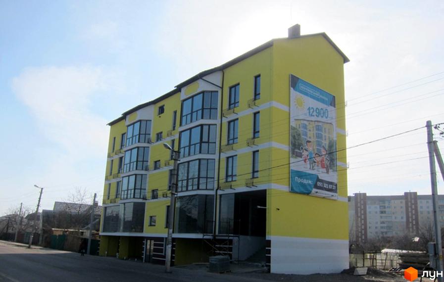 Житловий комплекс Шевченківський маєток – жовта новобудова з великими вікнами та рекламним банером. Поруч дорога та сусідні будинки.