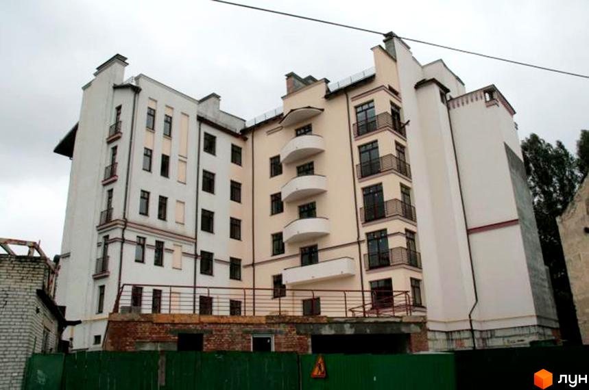 Новобудова на вулиці Левицького, 128, має білий та бежевий фасади з балконами та темними вікнами. Навколо будинку видно зелений паркан та будівельні роботи.