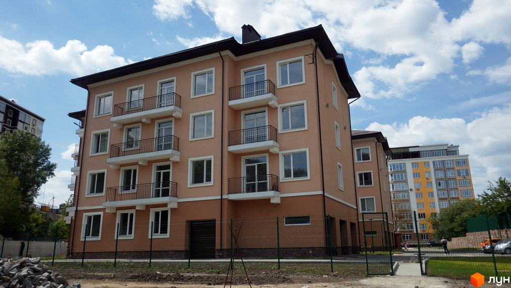 Зовнішній вигляд житлового комплексу BaikalSKY з балконами та вікнами. Навколо будинку розташована прибудинкова територія з парканом та зеленими насадженнями.