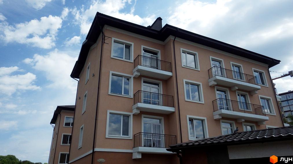 Фасад житлового комплексу BaikalSKY з балконами та вікнами на тлі блакитного неба з хмарами. Зовнішній вигляд новобудови.