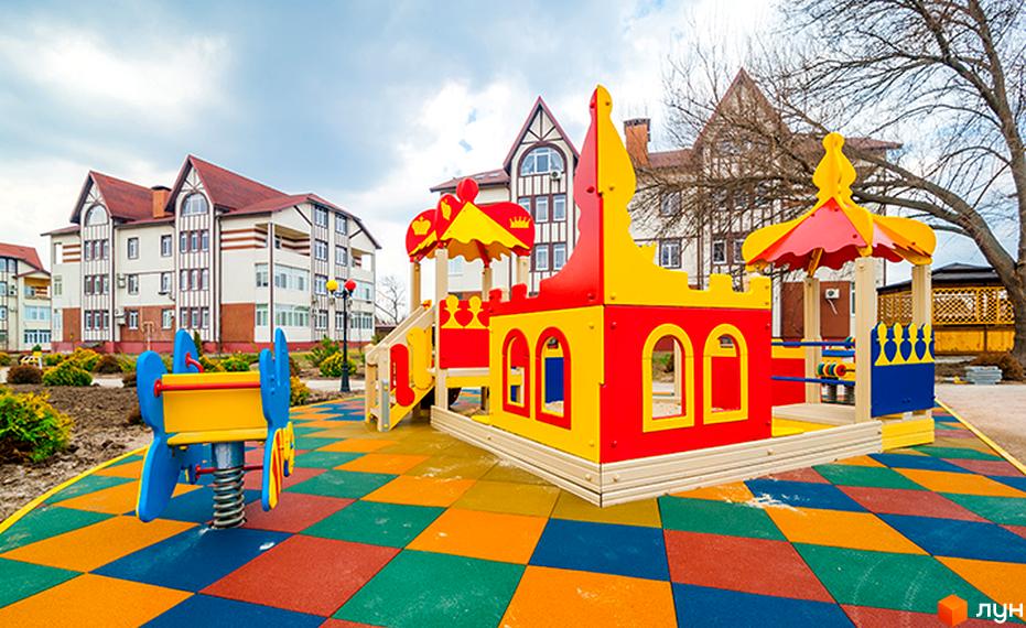 Зовнішній вигляд будинку житлового комплексу ЖК Ренесанс з кольоровим дитячим майданчиком на прибудинковій території.