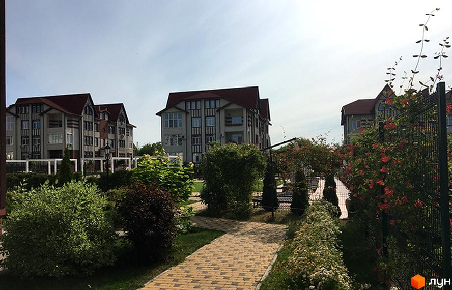 Житловий комплекс Ренесанс: триповерхові будинки з червоними дахами та сірими фасадами. Прибудинкова територія з доріжками, кущами та квітами.