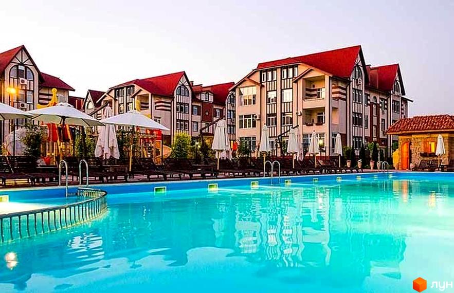 Житловий комплекс Ренесанс з червоними дахами та басейном. На території розташовані шезлонги та парасольки для відпочинку біля води.