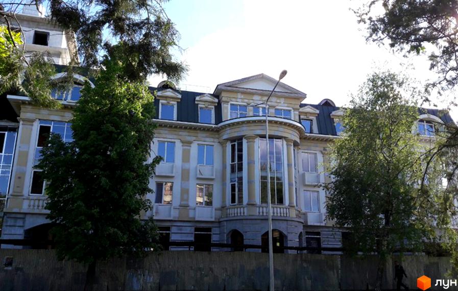 Житловий комплекс Парковий. Багатоповерхова будівля з заокругленим фасадом, колонами та великими вікнами, оточена деревами.