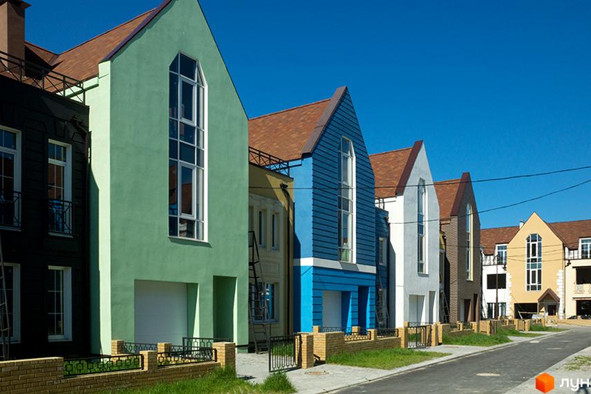Зовнішній вигляд таунхаусів у Житловому районі „Журавлевская Слобода“. Фасади будинків різних кольорів, великі вікна, доглянута прибудинкова територія.