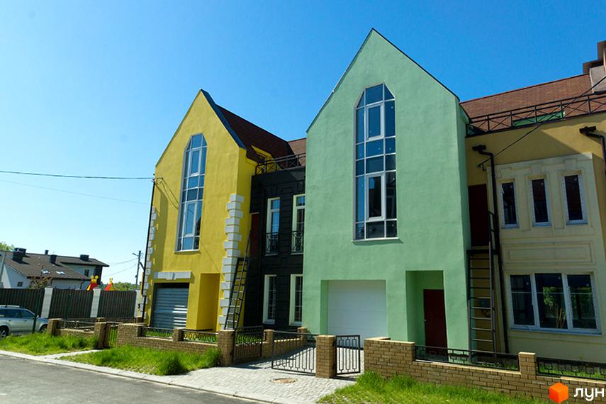 Зовнішній вигляд таунхаусів у Житловому районі „Журавлевская Слобода“. Двоповерхові будинки жовтого та зеленого кольорів з великими вікнами.