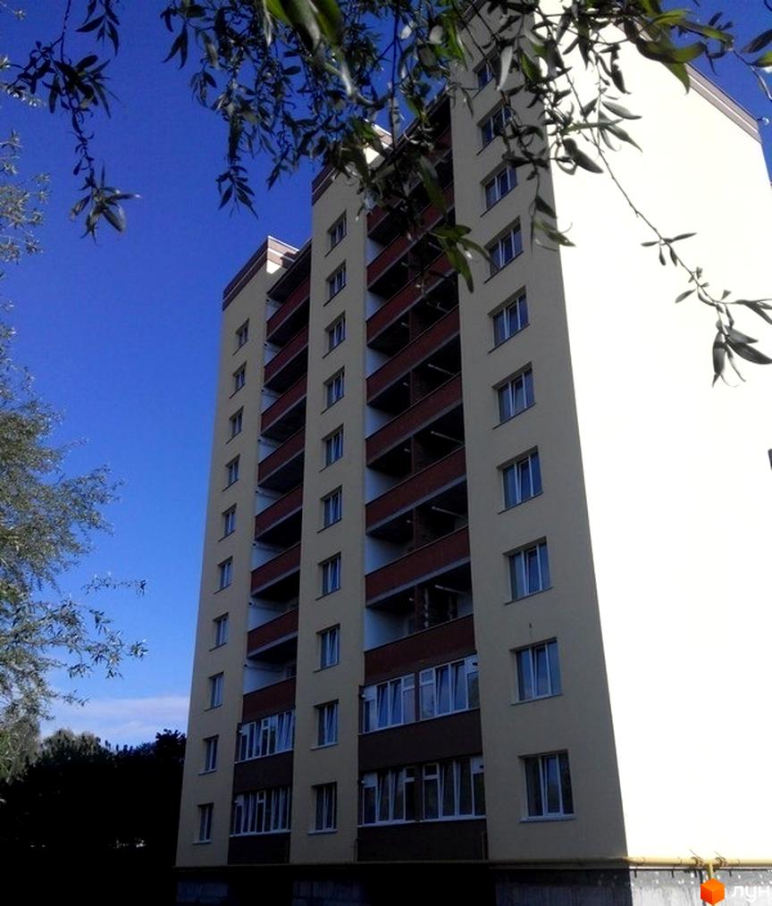 Фото багатоповерхового будинку на Старокостянтинівському шосе, 5/3. Житловий комплекс з балконами та великими вікнами на фоні блакитного неба.