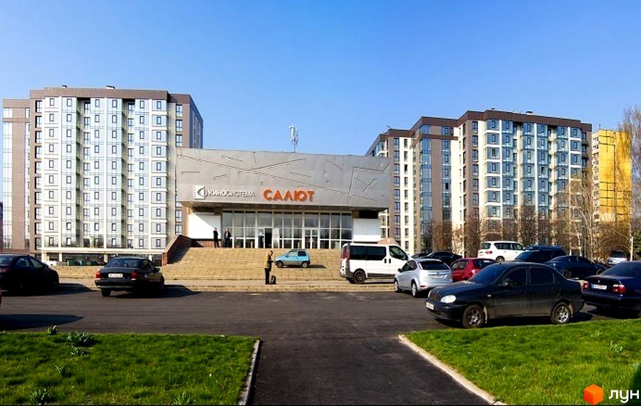 Житловий комплекс Салют – це сучасна новобудова з великою кількістю вікон та парковкою біля входу. Навколо комплексу розташовані зелені насадження та доглянуті газони.