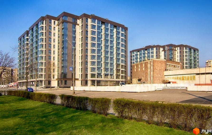 Житловий комплекс Салют. Сучасні багатоповерхові будинки з панорамними вікнами та доглянутою прибудинковою територією з зеленими насадженнями.