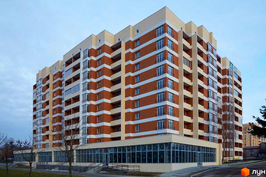 Фасад новобудови на вул. Перфецького, 2а, з цегляним оздобленням та великими вікнами. Навколо будинку облаштована прибудинкова територія з деревами та доріжками.