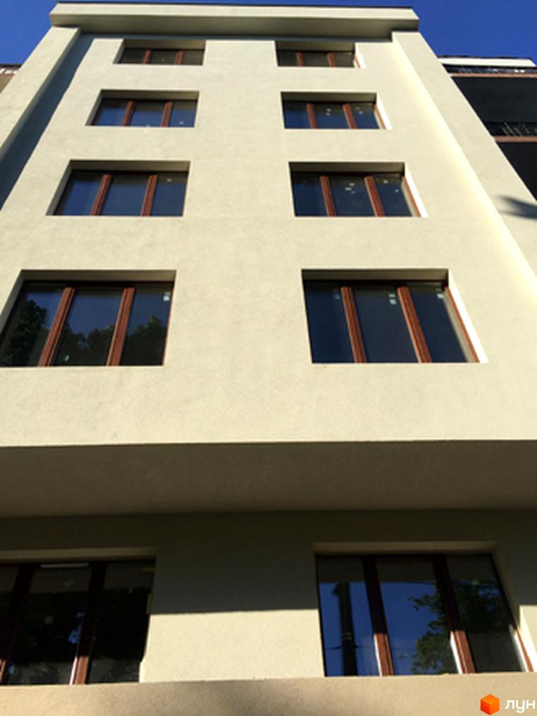 Зображення фасаду будинку житлового комплексу Brownie House. Висока будівля з великими вікнами та світлим фасадом.