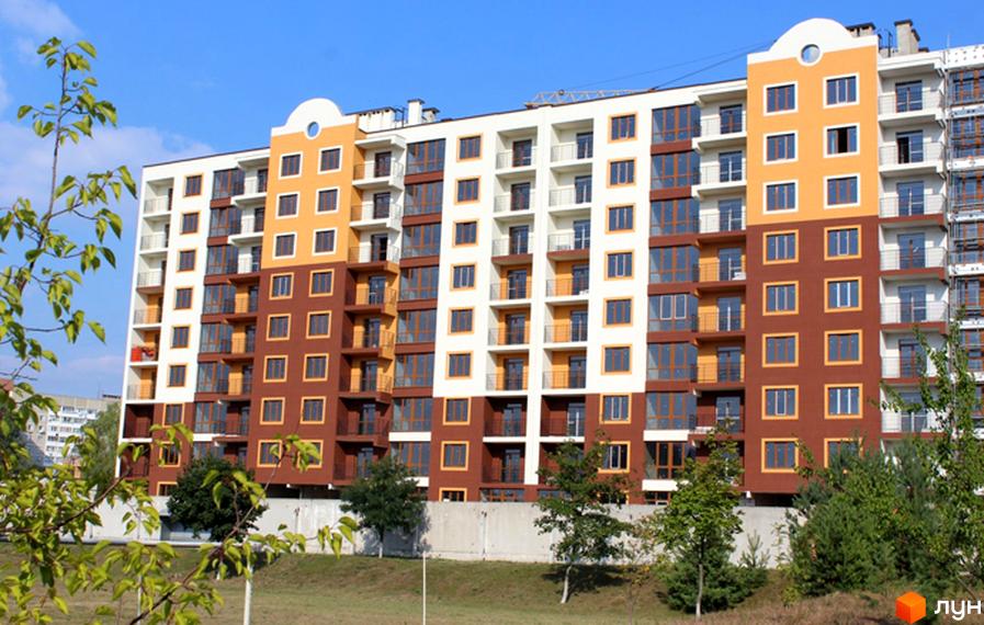 Житловий комплекс Паркове містечко - багатоповерховий будинок з коричневими та жовтими фасадами, балконами та великими вікнами. Навколо будинку зелені насадження та блакитне небо.