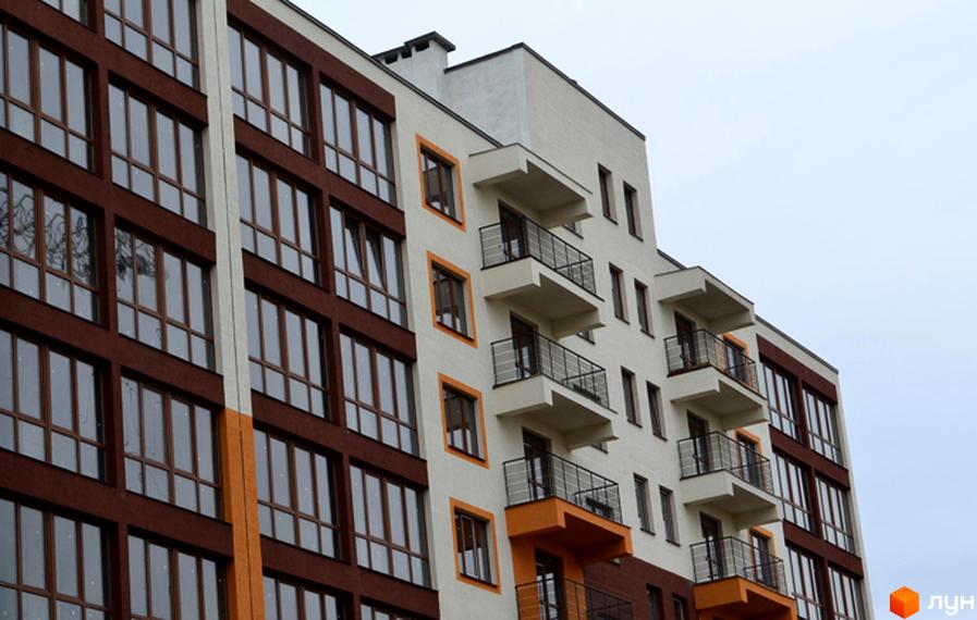 Зовнішній вигляд новобудови ЖК Паркове містечко з коричневими та білими фасадами, великими вікнами та балконами. Будівельний проєкт з сучасною архітектурою.