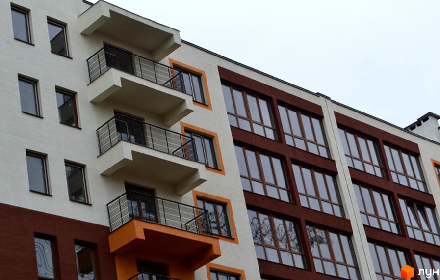Фасад житлового комплексу Паркове містечко з балконами та великими вікнами. Зовнішній вигляд новобудови з білою та коричневою обробкою.