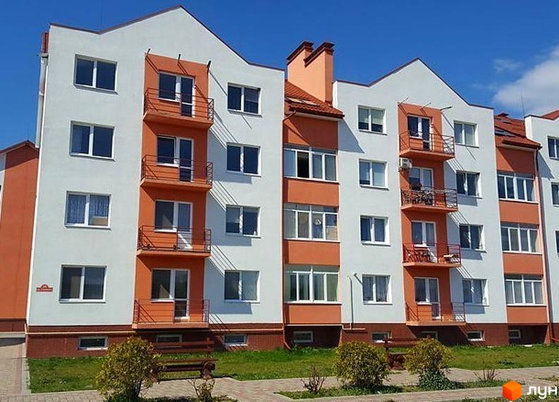 Житловий комплекс Озерний край - фасади будівель з помаранчевими та білими елементами, балконами та вікнами. Навколо будівель зелена зона з лавками та кущами.