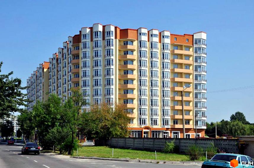 Житловий комплекс на вул. Лінкольна, 10 – багатоповерхова новобудова з жовто-білим фасадом та балконами. Поруч зелена зона та дорога.
