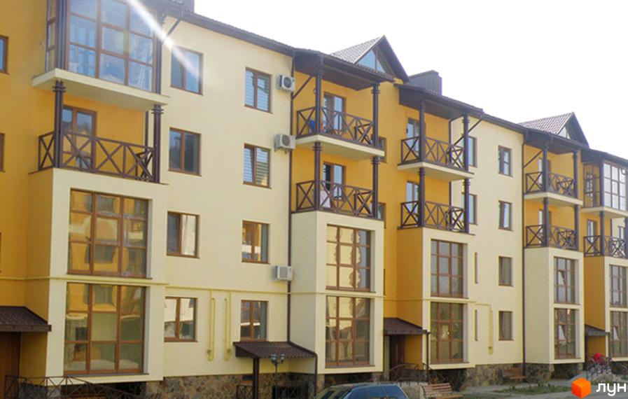 Зовнішній вигляд новобудови ЖК Віденська брама. Фасад будинку виконаний у жовтих та бежевих тонах, з балконами та великими вікнами. На прибудинковій території видно зелені насадження та лавки.