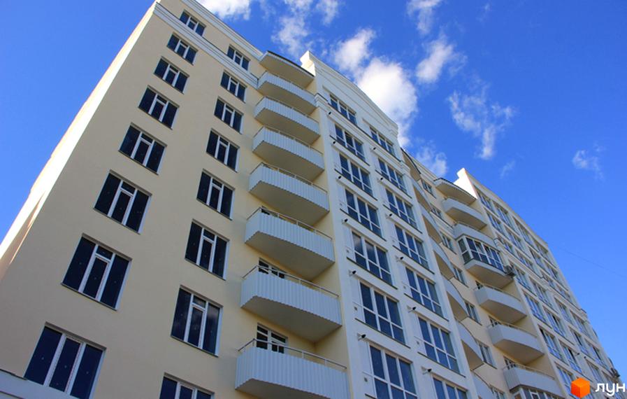 Фасад новобудови на вул. Милорадовичів (Петровського), 55, ул. Володимира Івасюка (Менделєєва), 5, з численними вікнами та балконами на фоні блакитного неба з хмарами.