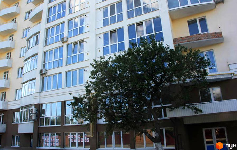 Фасад новобудови на вулиці Милорадовичів (Петровського), 55, ул. Володимира Івасюка (Менделєєва), 5. Будинок має багато вікон та балконів, а перед ним росте дерево.