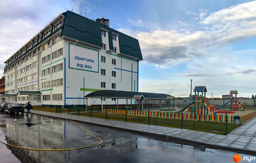Житловий комплекс Милі квартири: біла багатоповерхівка з зеленим дахом та дитячим майданчиком. Новобудова з квартирами від ЖБК.