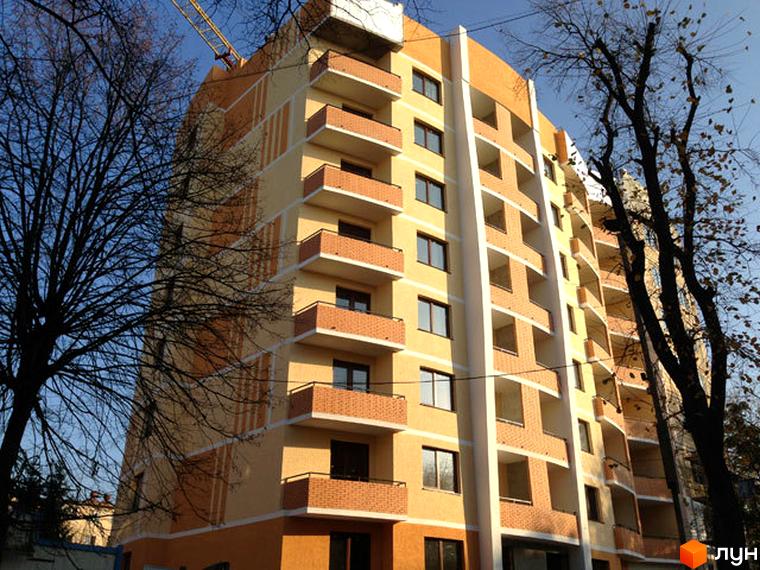 Сучасна новобудова на вулиці Городоцькій, 245а. Фасад будинку оздоблений цеглою та світлими панелями, з численними балконами. Навколо ростуть дерева.