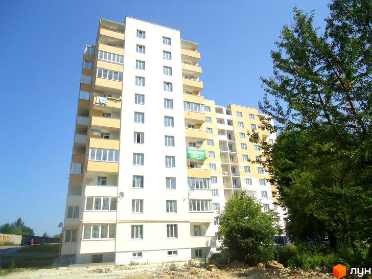 Зовнішній вигляд новобудови на вулиці Під Голоском, 8. Багатоповерховий житловий комплекс з жовтими та білими фасадами, балконами та великими вікнами. Навколо зелені насадження та елементи благоустрою.