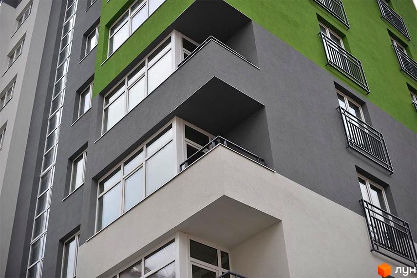 Житловий комплекс Пасічний – це будівля з контрастним сіро-зеленим фасадом, балконами з металевими огорожами та великими вікнами.
