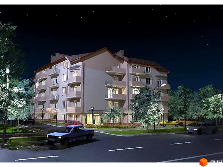 Зовнішній вигляд 6-поверхового житлового комплексу з балконами та вікнами, розташованого біля дороги з автомобілями та деревами вночі. Навколо комплексу зелена територія з освітленням.