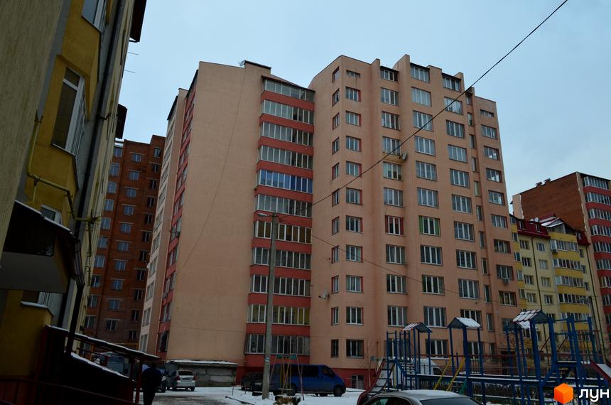 Зовнішній вигляд багатоповерхових будинків житлового комплексу Львівська брама. На прибудинковій території видно дитячий майданчик та припарковані автомобілі.