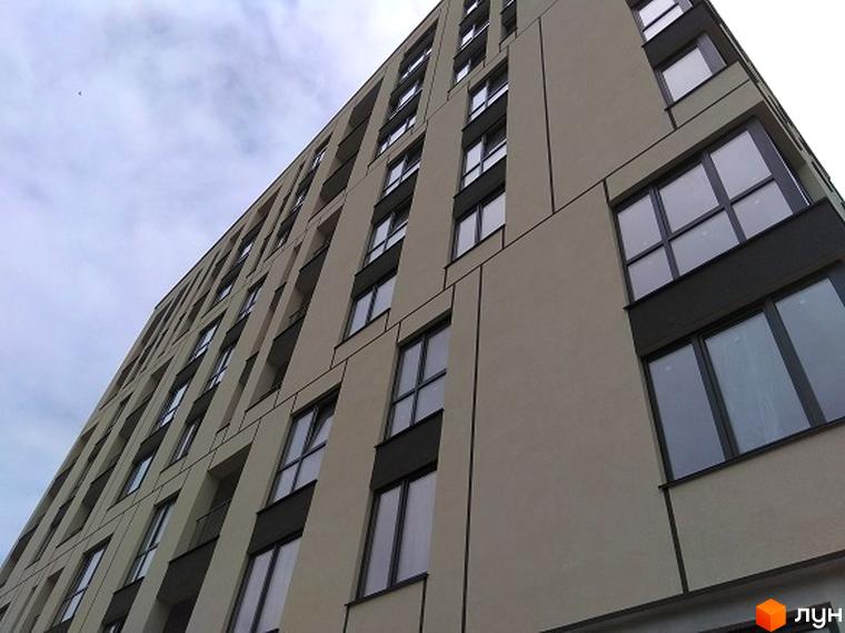 Зовнішній вигляд новобудови ЖК Spectrum з великою кількістю вікон та балконів. Будинок має сучасний дизайн з сірими та бежевими елементами фасаду.