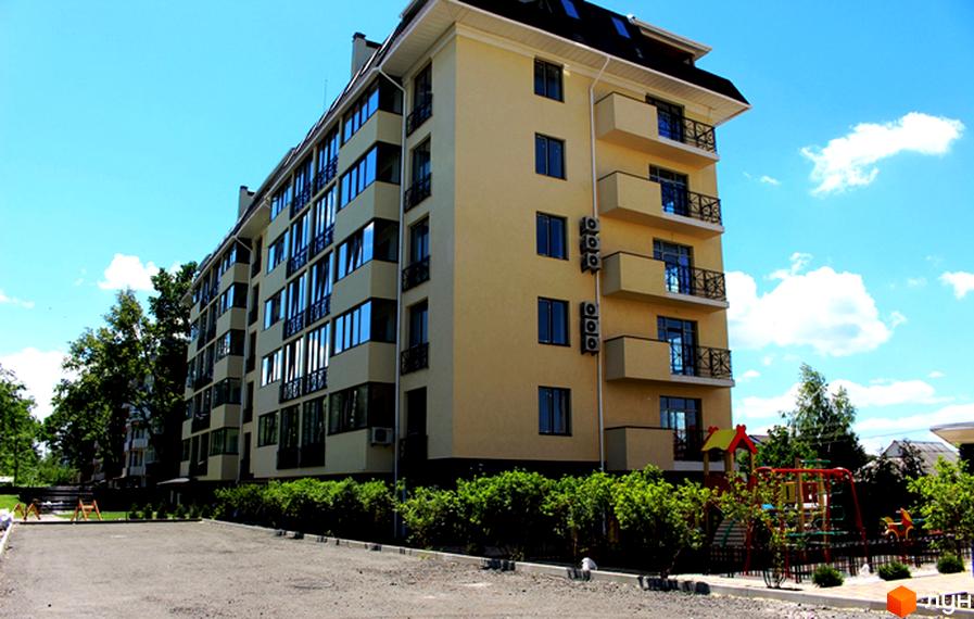 Житловий комплекс Almond apartments - це багатоповерхова будівля світло-жовтого кольору з численними вікнами та балконами. Перед будинком розташований дитячий майданчик та зелені насадження.